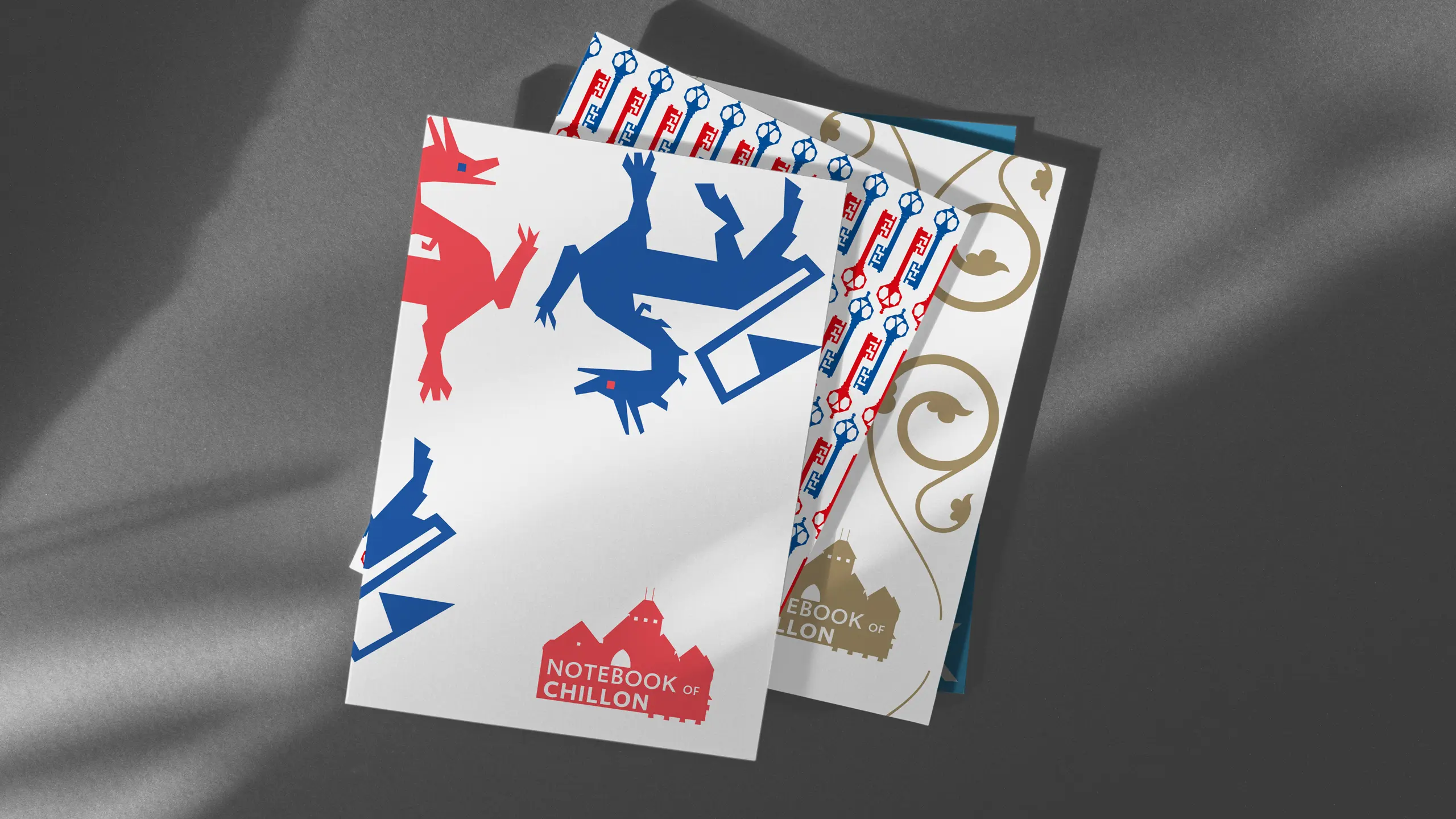 Trois carnets « Notebook of Chillon » présentant les motifs dragons, clés et ferronnerie du système graphique